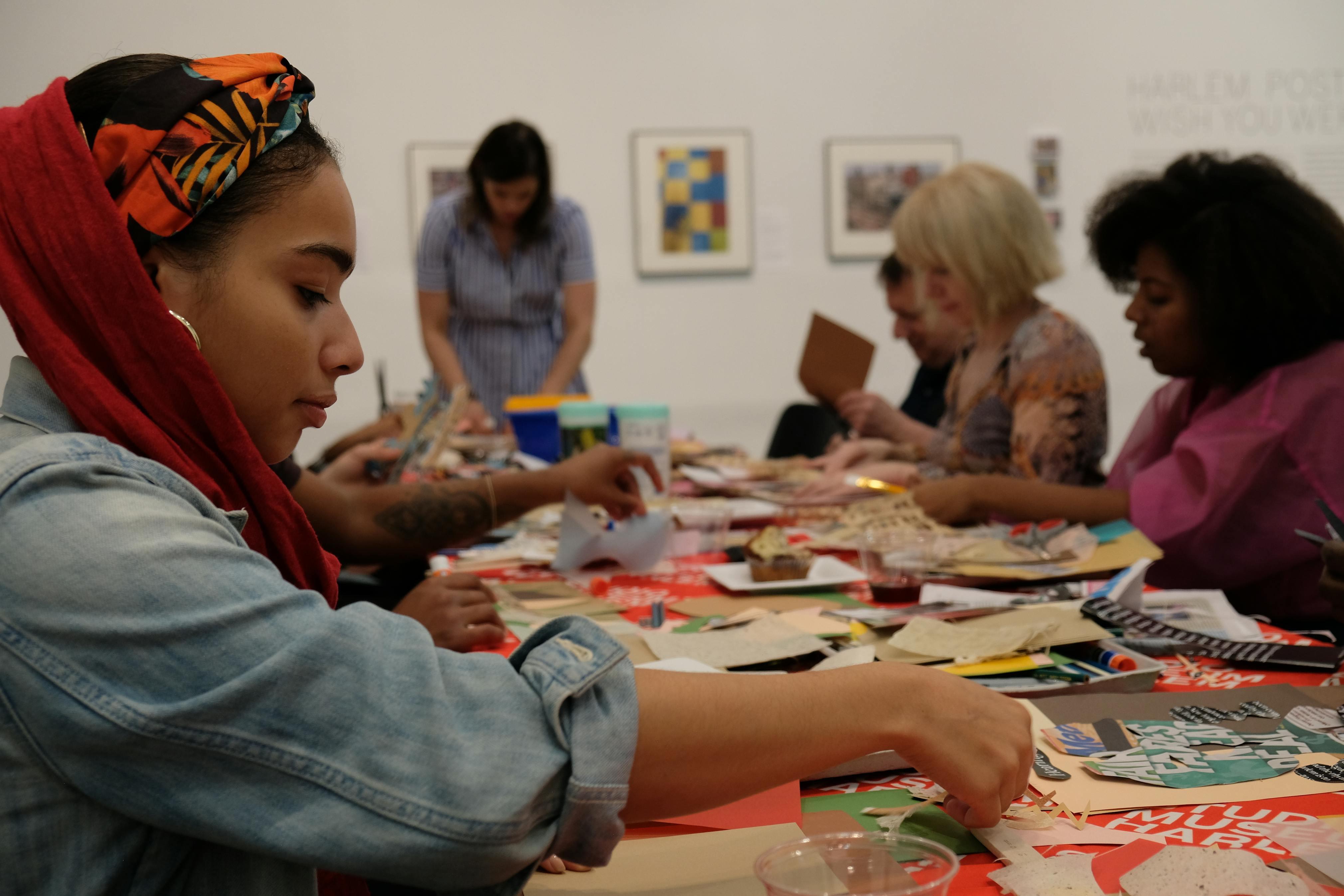 Group of people handling colorful pieces of paper at a rectangular table.